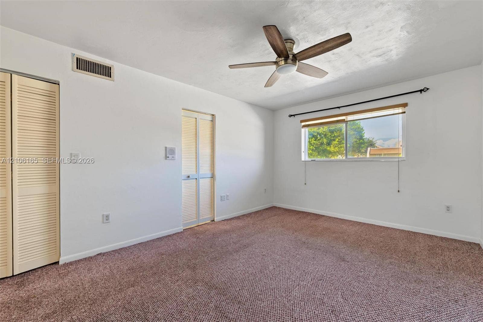 7205 W 3rd Avenue, #1, Hialeah, Hialeah, FL 33014 Neutral-toned carpeting, dual louvered-style closet doors, and a ceiling fan with integrated lighting
