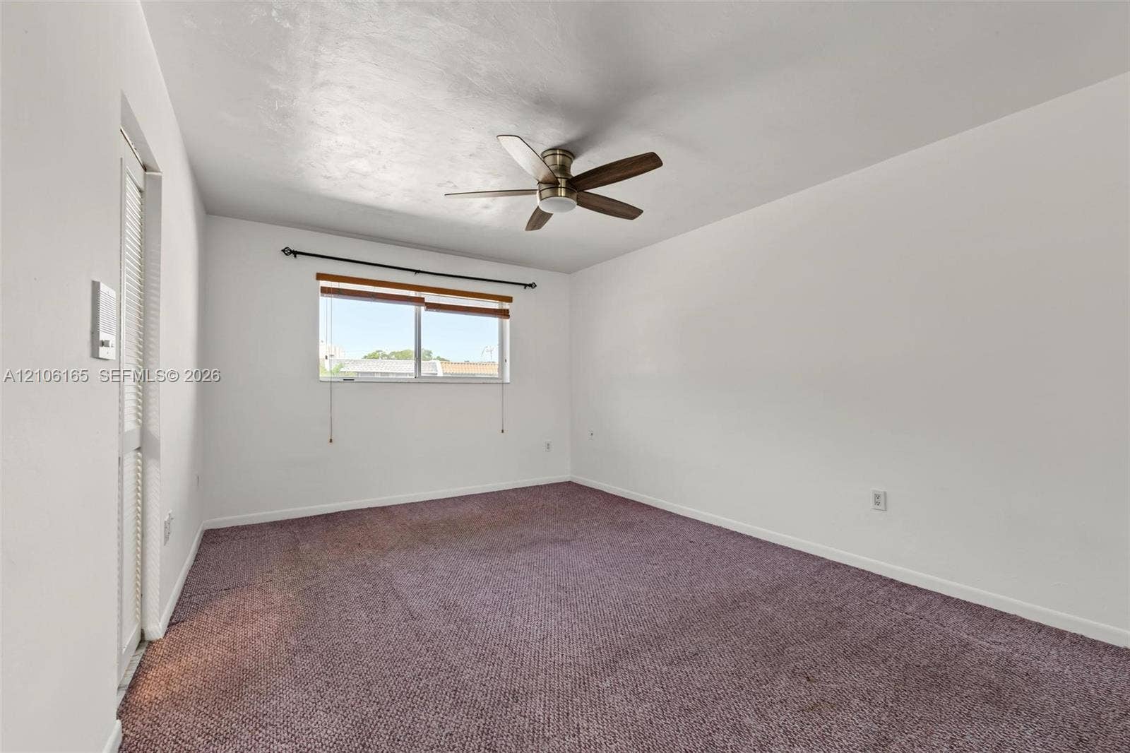 7205 W 3rd Avenue, #1, Hialeah, Hialeah, FL 33014 Interior room featuring wall-to-wall carpeting, a ceiling fan with integrated light fixture, a single-hung window with a dark metal curtain rod, and a louvered bi-fold closet door