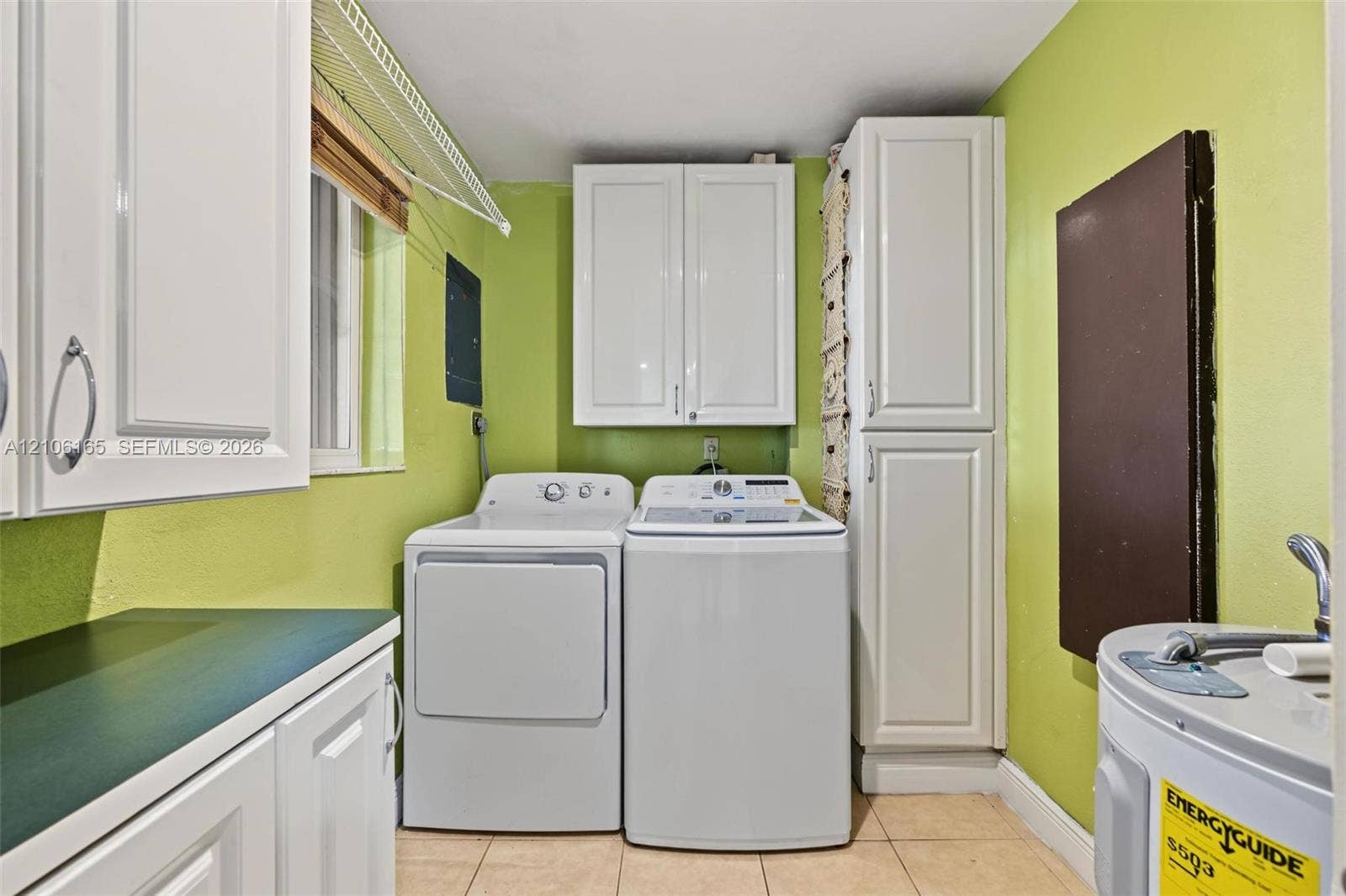 7205 W 3rd Avenue, #1, Hialeah, Hialeah, FL 33014 Laundry space featuring white shaker-style cabinetry, a full-height pantry cabinet, tile flooring, and a wire shelving unit