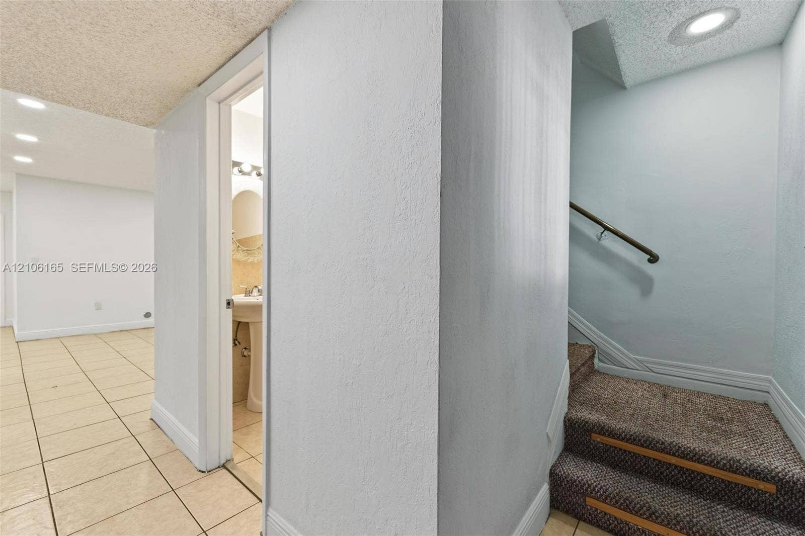 7205 W 3rd Avenue, #1, Hialeah, Hialeah, FL 33014 Staircase with carpeted steps, a wall-mounted metal handrail, recessed ceiling lighting, light-toned floor tiling, and a pedestal sink