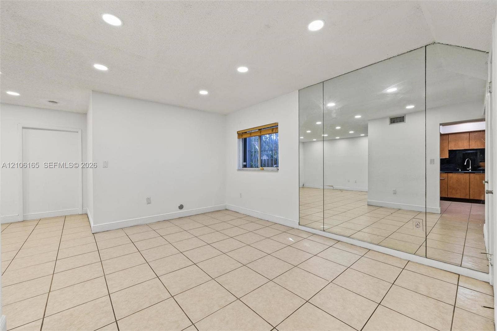 7205 W 3rd Avenue, #1, Hialeah, Hialeah, FL 33014 Interior space featuring neutral tile flooring, recessed ceiling lighting, a floor-to-ceiling mirrored wall, and a single window