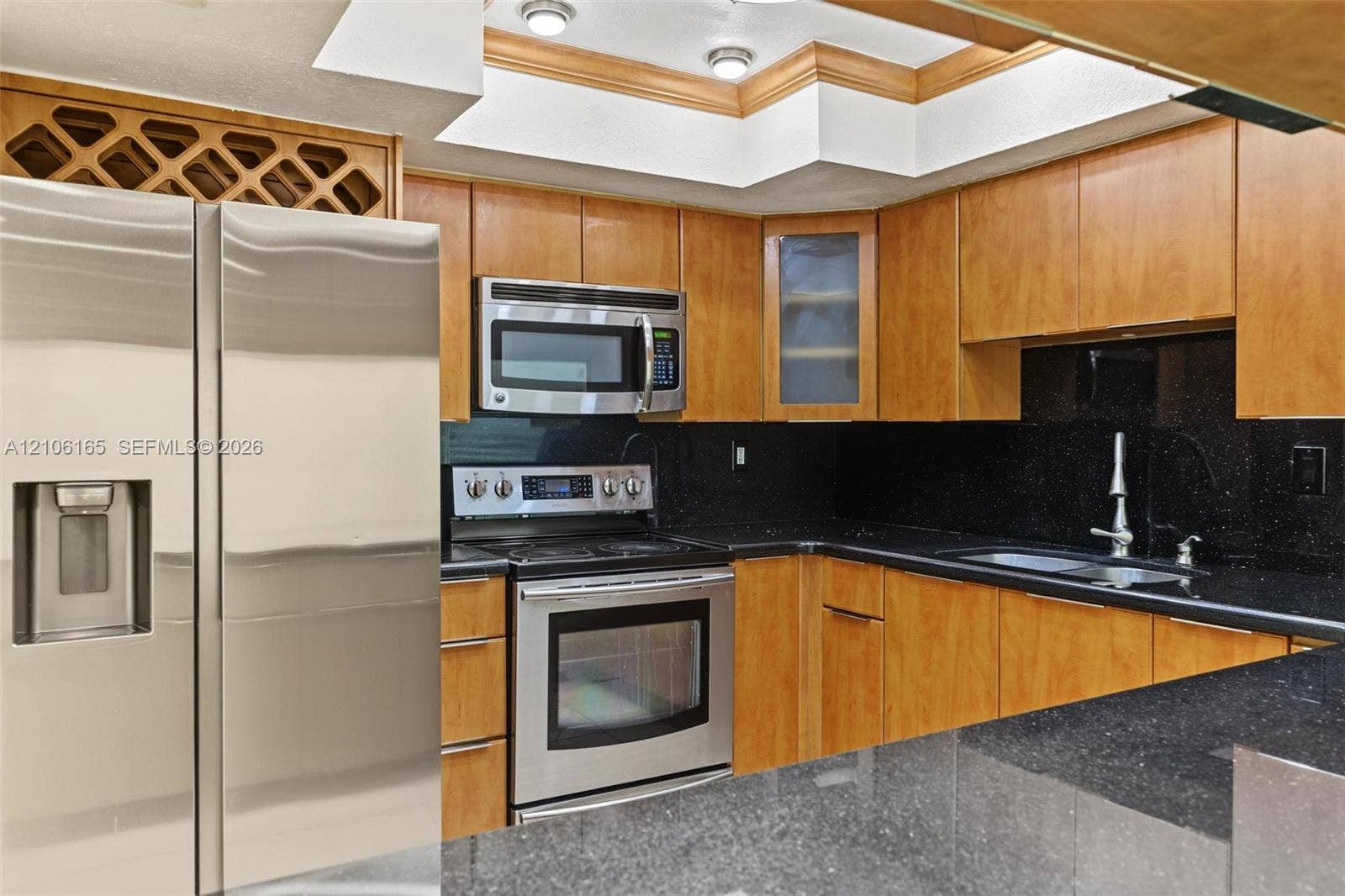 7205 W 3rd Avenue, #1, Hialeah, Hialeah, FL 33014 Kitchen featuring wood cabinetry, stainless steel appliances, dark stone-finish countertops, built-in wine storage, and a tray ceiling with recessed lighting