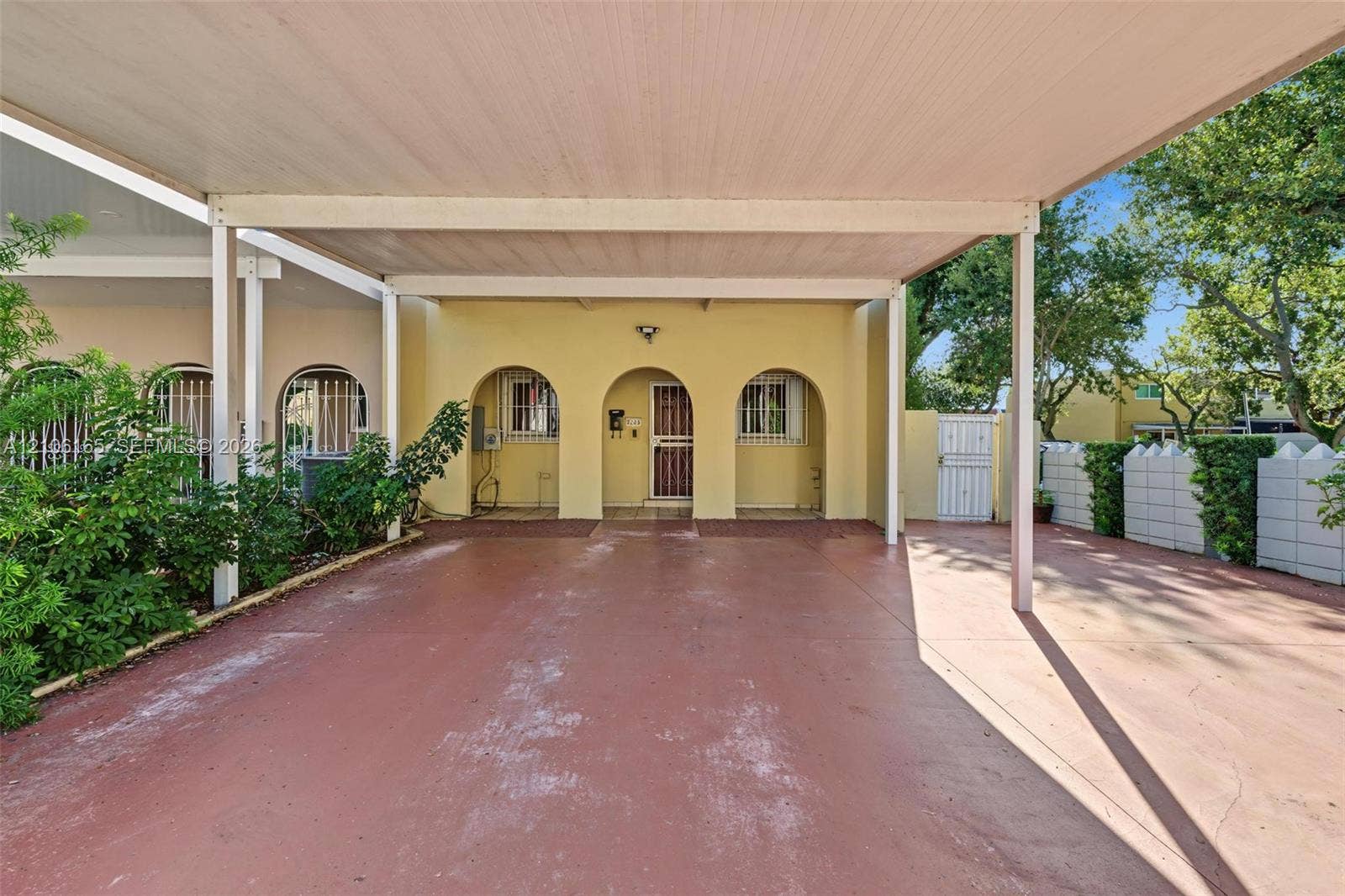 7205 W 3rd Avenue, #1, Hialeah, Hialeah, FL 33014 Covered carport featuring a concrete surface, arched architectural detailing, and a gated side entrance