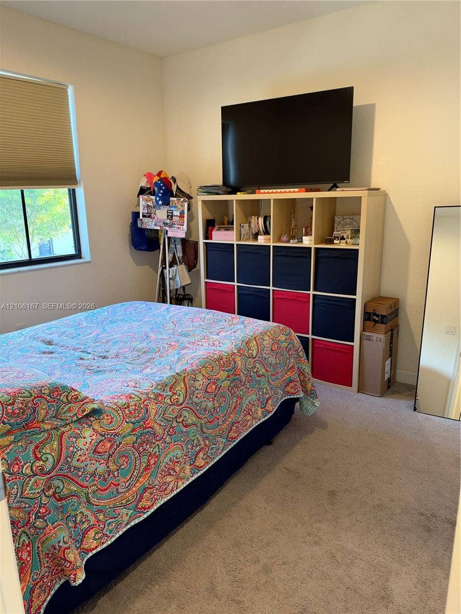 3277 W 100th Terrace, Hialeah, FL 33018 Neutral-toned walls, wall-to-wall carpeting, and a large window with a pleated shade