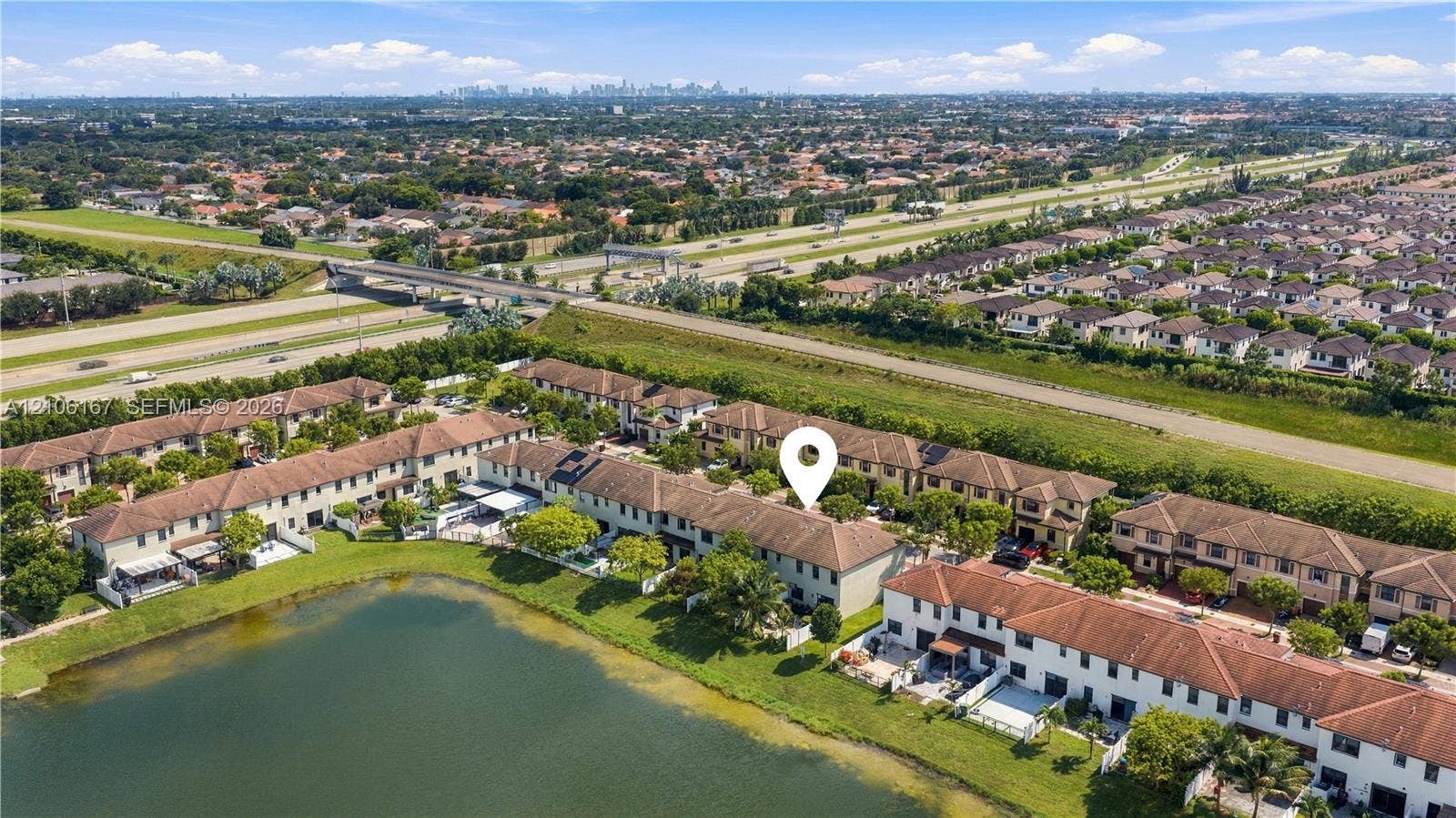 3277 W 100th Terrace, Hialeah, FL 33018 Aerial perspective of a multi-unit residential complex featuring tile roofing and waterfront positioning along a private pond