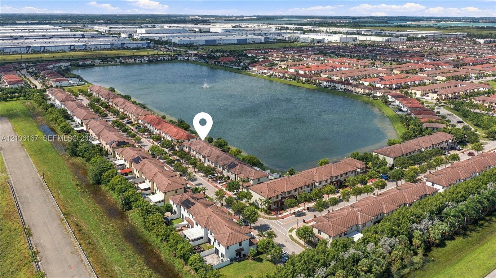 3277 W 100th Terrace, Hialeah, FL 33018 Aerial perspective of a multi-unit residential community featuring clay tile roofing and waterfront positioning along a central lake