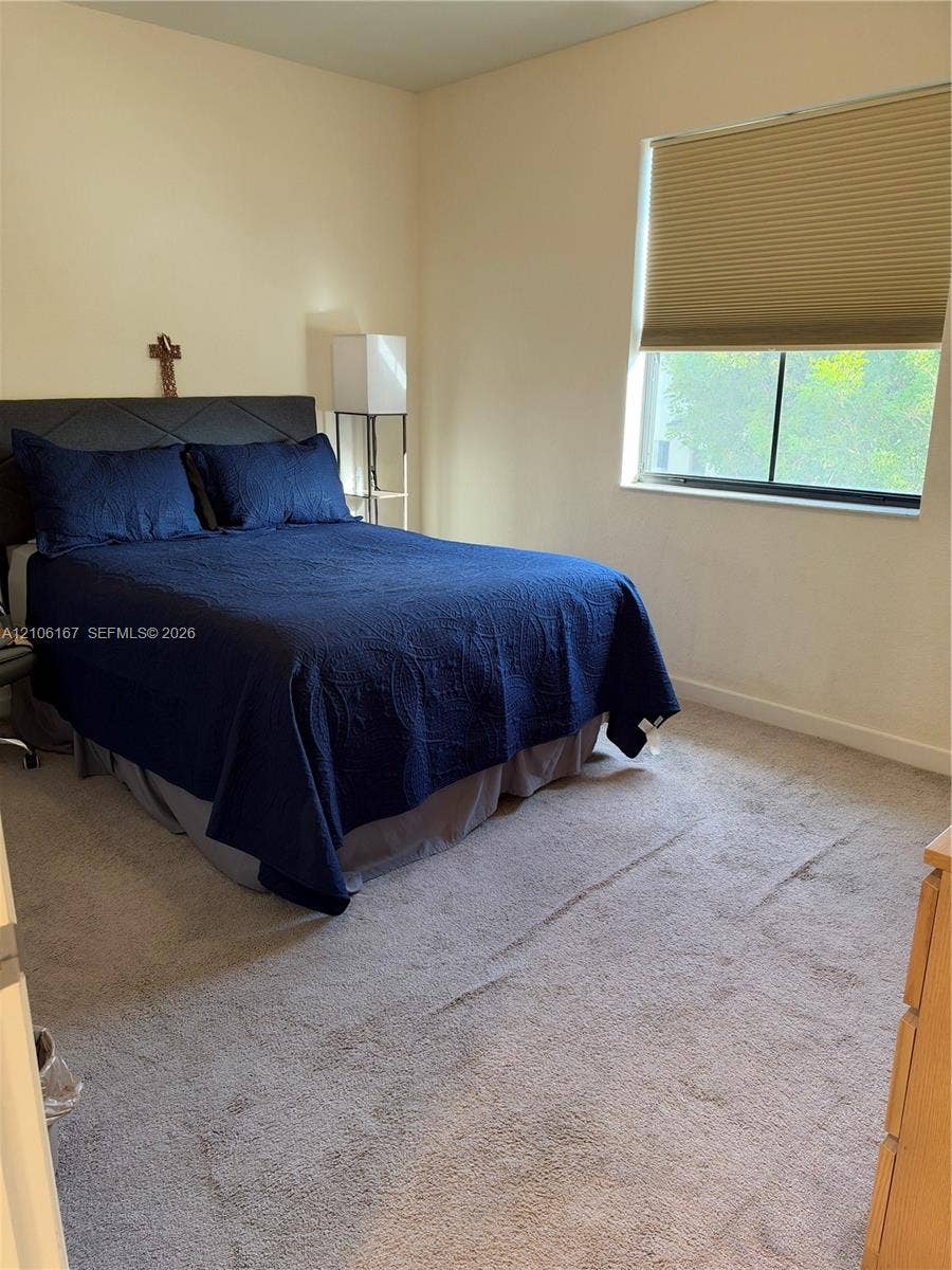 3277 W 100th Terrace, Hialeah, FL 33018 Neutral-toned interior space featuring neutral wall paint, wall-to-wall carpeting, and a window with a cellular shade