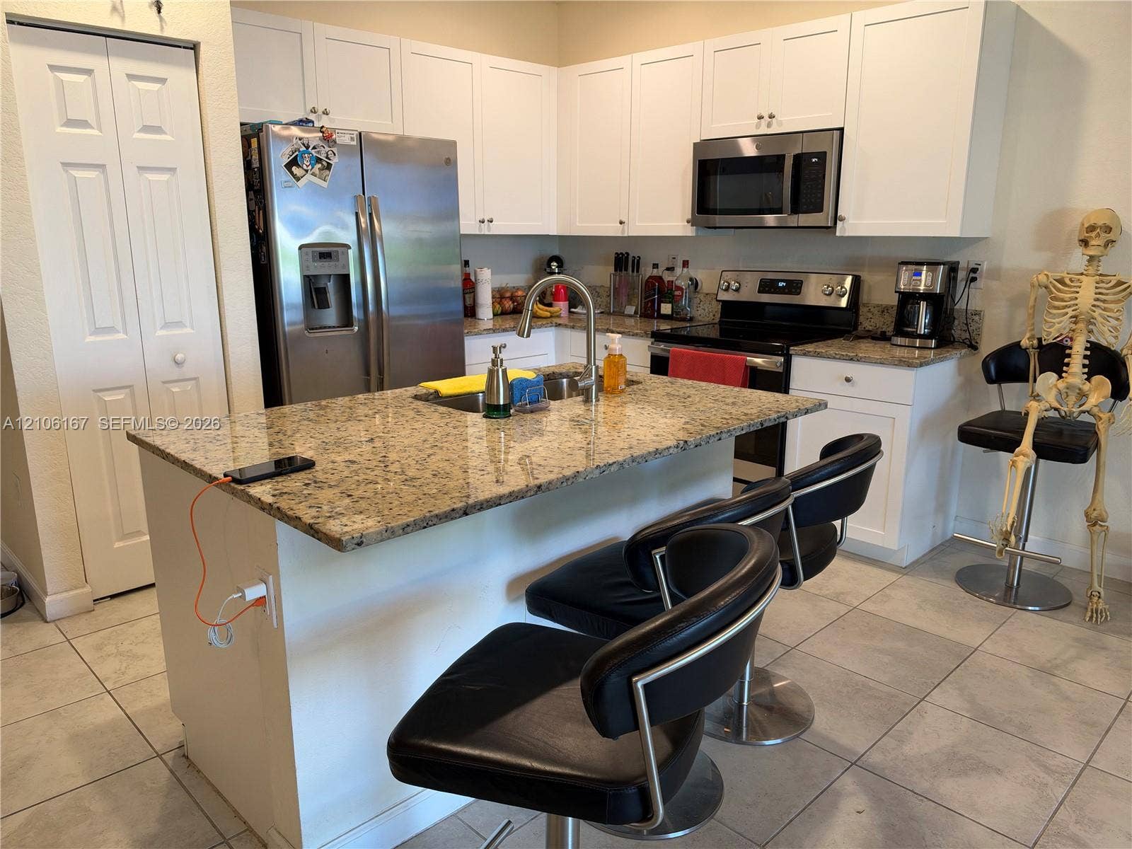 3277 W 100th Terrace, Hialeah, FL 33018 Kitchen featuring white cabinetry, stone countertops, central island with stainless steel faucet, and stainless steel appliances