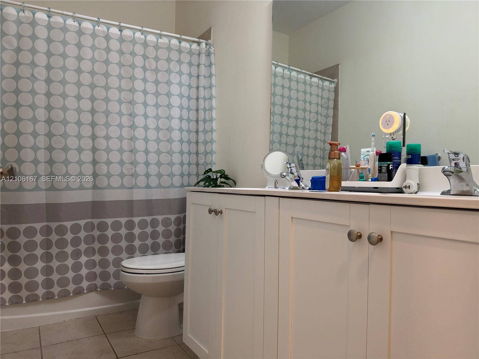 3277 W 100th Terrace, Hialeah, FL 33018 White shaker-style vanity cabinet with metallic hardware, integrated countertop with a basin sink, polished chrome faucet, and large-format wall-mounted mirror
