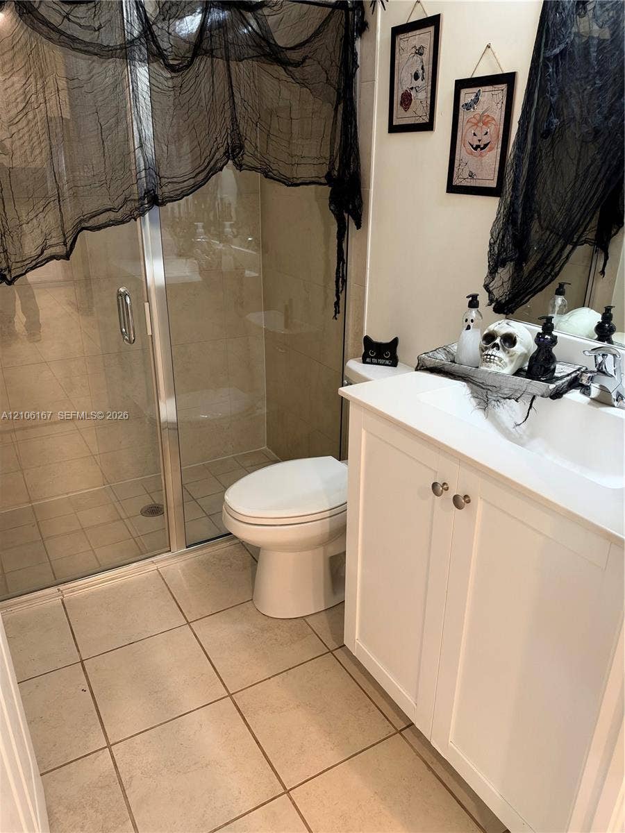 3277 W 100th Terrace, Hialeah, FL 33018 Bathroom featuring a white vanity cabinet with a rectangular basin, chrome faucet, shower enclosure with a glass door, and neutral tile flooring