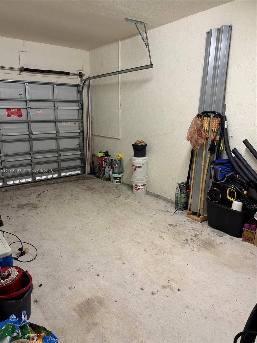 3277 W 100th Terrace, Hialeah, FL 33018 Garage featuring a metal sectional roll-up door and concrete flooring