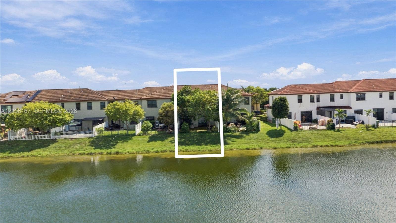 3277 W 100th Terrace, Hialeah, FL 33018 Waterfront exterior featuring a multi-story stucco facade, tiled roof, and expansive lawn bordering the canal