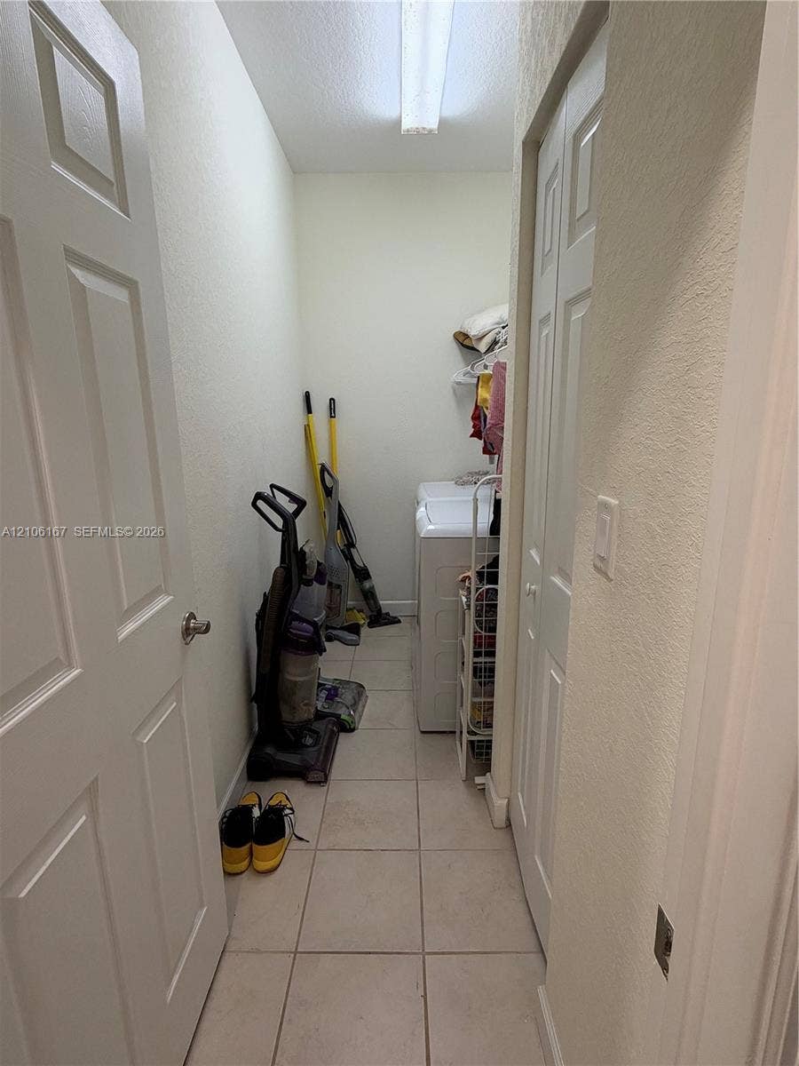 3277 W 100th Terrace, Hialeah, FL 33018 Utility space featuring ceramic tile flooring, neutral wall finishes, overhead lighting, and built-in shelving