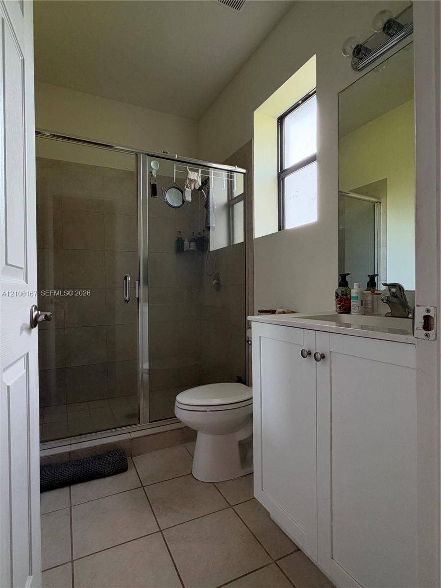3277 W 100th Terrace, Hialeah, FL 33018 Bathroom featuring a shower with a glass enclosure, white vanity cabinet, rectangular countertop sink, wall-mounted mirror, and tile flooring