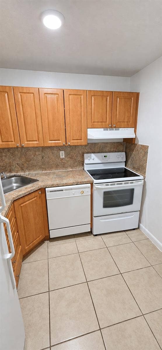 10820 SW 200th Drive, #162, Cutler Bay, Cutler Bay, FL 33157 Kitchen featuring wood cabinetry, solid-surface countertops, tile flooring, and white built-in appliances including a dishwasher and electric range
