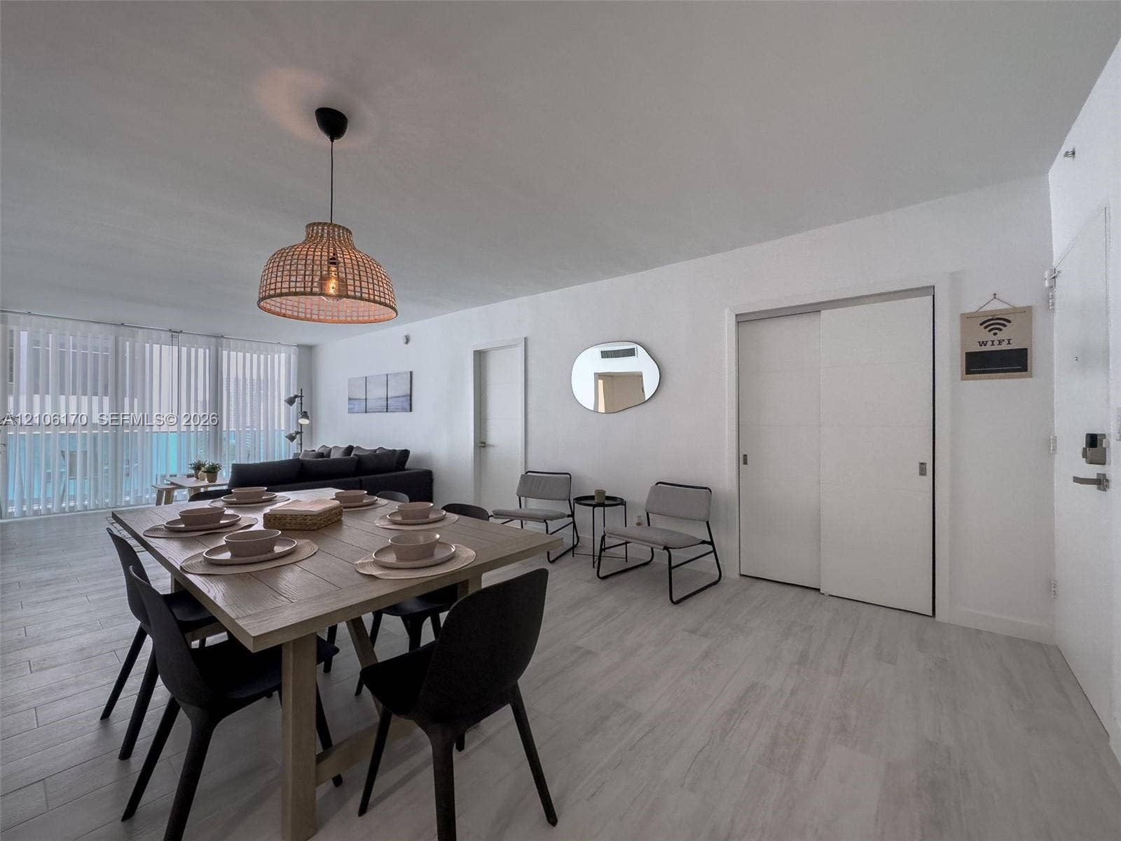 4001 S Ocean Drive, #12B, Hollywood, Hollywood, FL 33019 Open-concept area featuring light-toned wood-finish flooring, floor-to-ceiling vertical blinds, a woven dome pendant light, and a double-door sliding closet