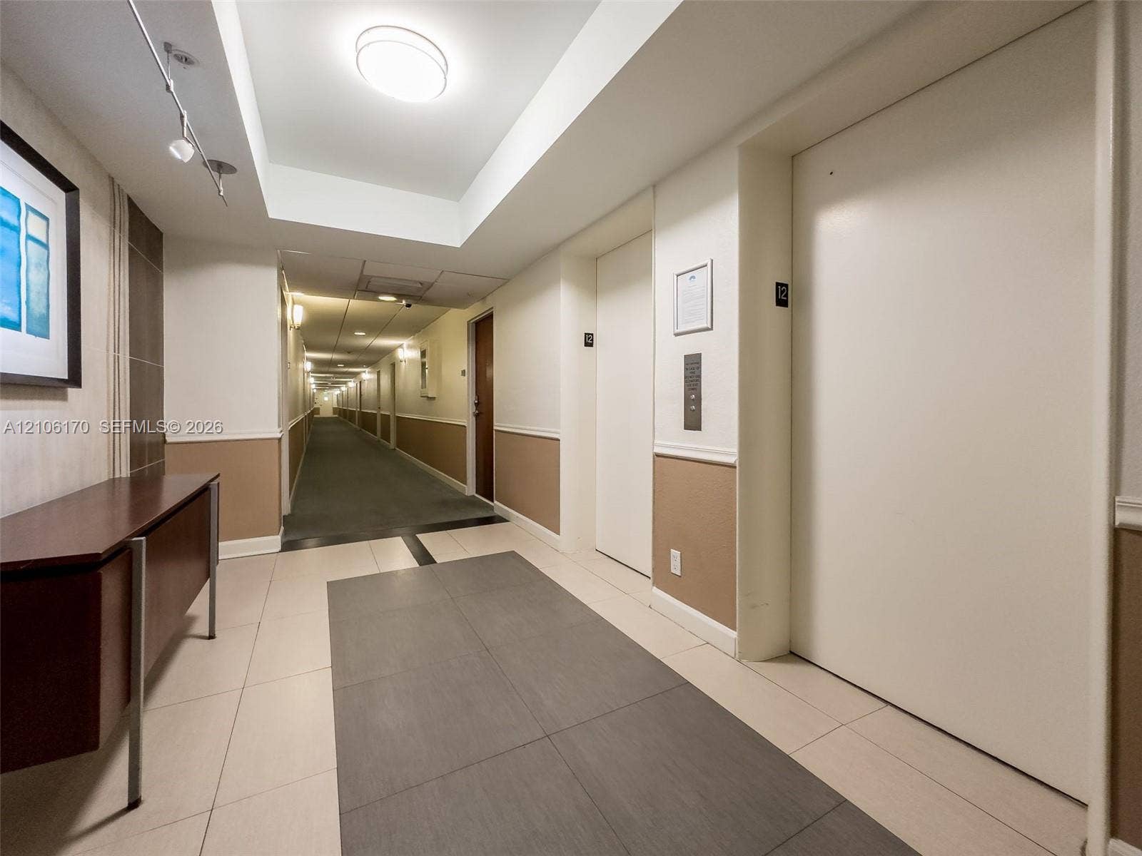 4001 S Ocean Drive, #12B, Hollywood, Hollywood, FL 33019 Elevator landing featuring recessed tray ceiling, neutral wall finishes with wainscoting, large-format tile flooring, and integrated lighting
