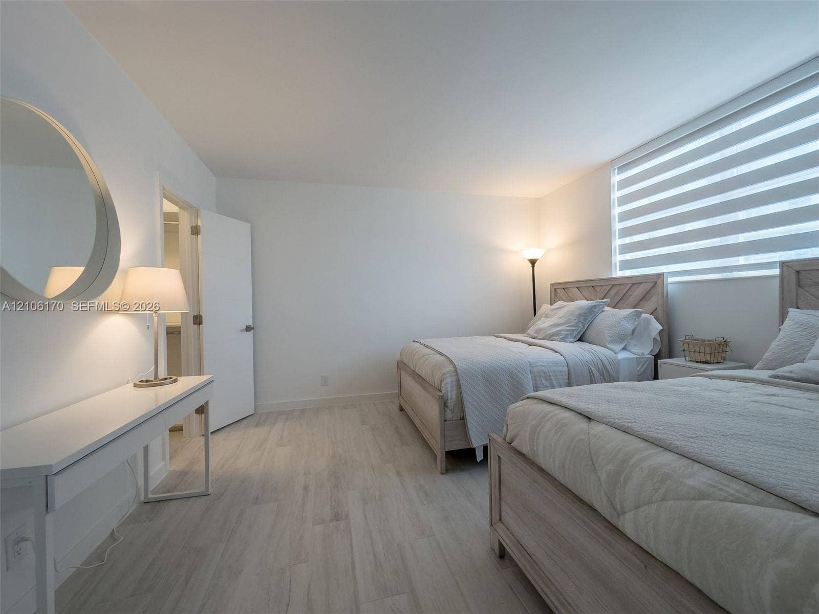 4001 S Ocean Drive, #12B, Hollywood, Hollywood, FL 33019 Bedroom featuring wood-finish flooring, a wall-mounted round mirror, and horizontal-slat window shades