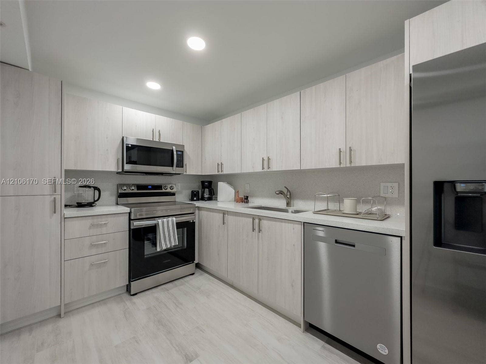 4001 S Ocean Drive, #12B, Hollywood, Hollywood, FL 33019 Kitchen featuring light wood-finish cabinetry, stainless steel appliances, solid surface countertops, and wood-finish flooring