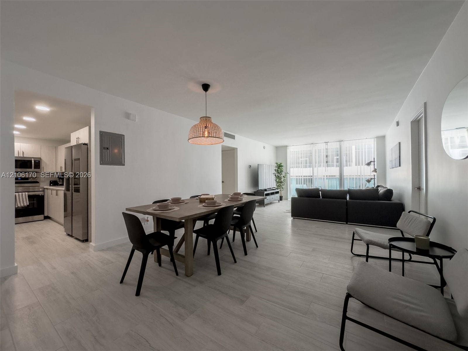 4001 S Ocean Drive, #12B, Hollywood, Hollywood, FL 33019 Open-concept interior featuring light wood-finish flooring, a neutral color palette, recessed lighting, a woven drum pendant light, and floor-to-ceiling windows