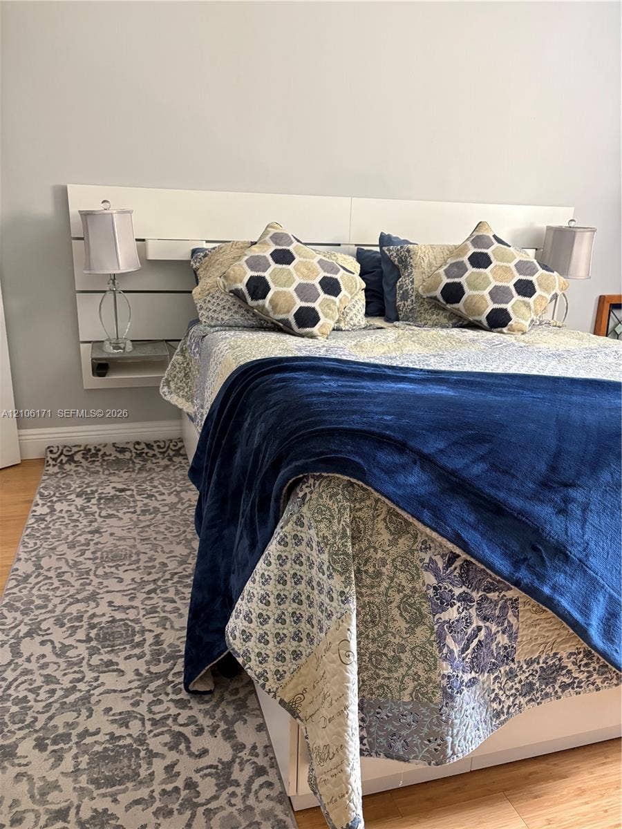 Built-in white horizontal paneled headboard with integrated floating nightstands and wood-finish flooring