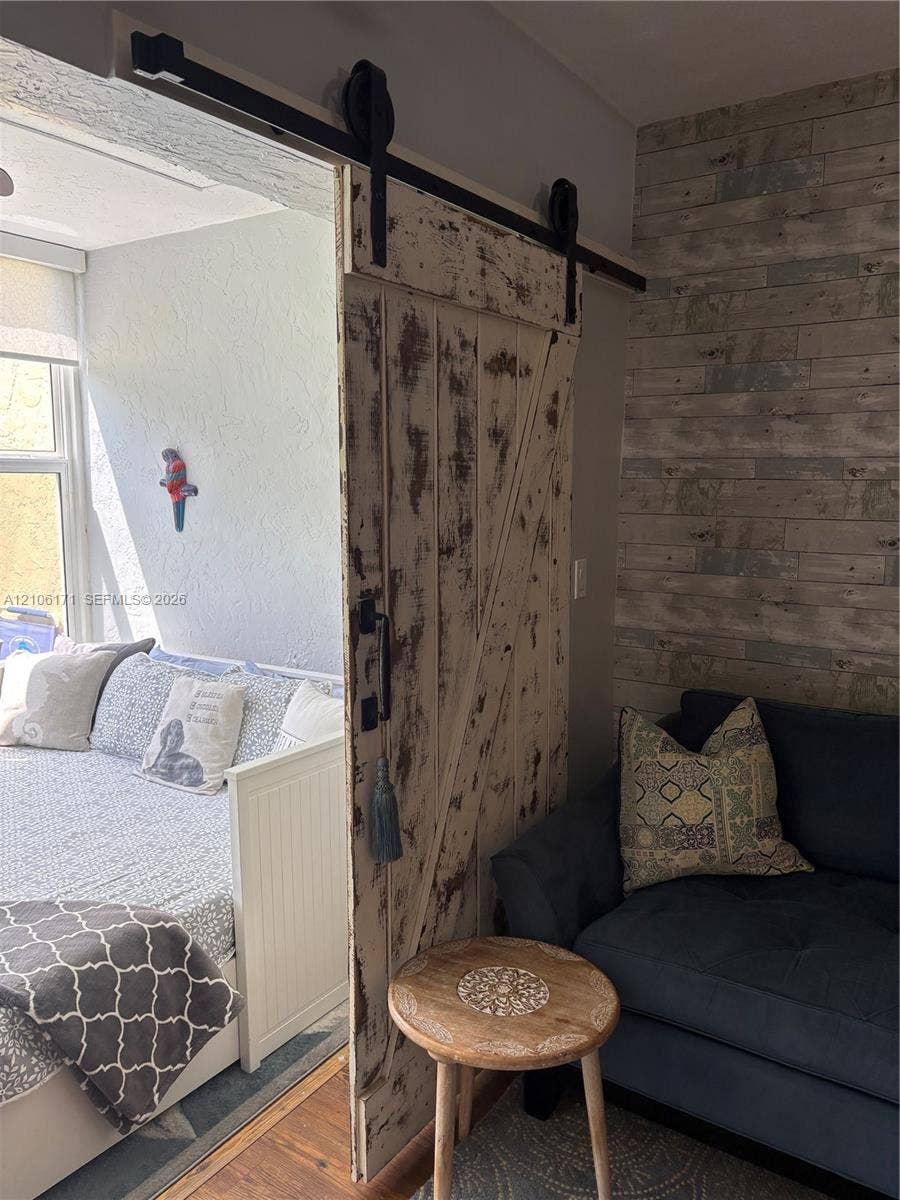 Distressed white sliding barn door on a black industrial-style hardware track, featuring horizontal wood-plank accent wall paneling