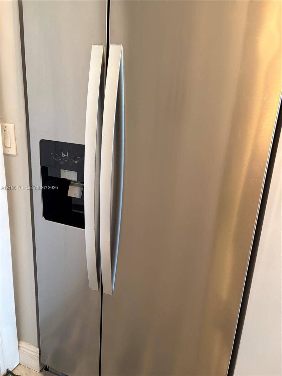 Stainless steel side-by-side refrigerator featuring an integrated door-mounted water and ice dispenser