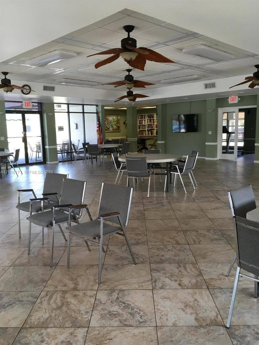 Open-concept space featuring tile flooring, a tray ceiling with recessed lighting, multiple ceiling fans, and large glass-paneled exterior doors