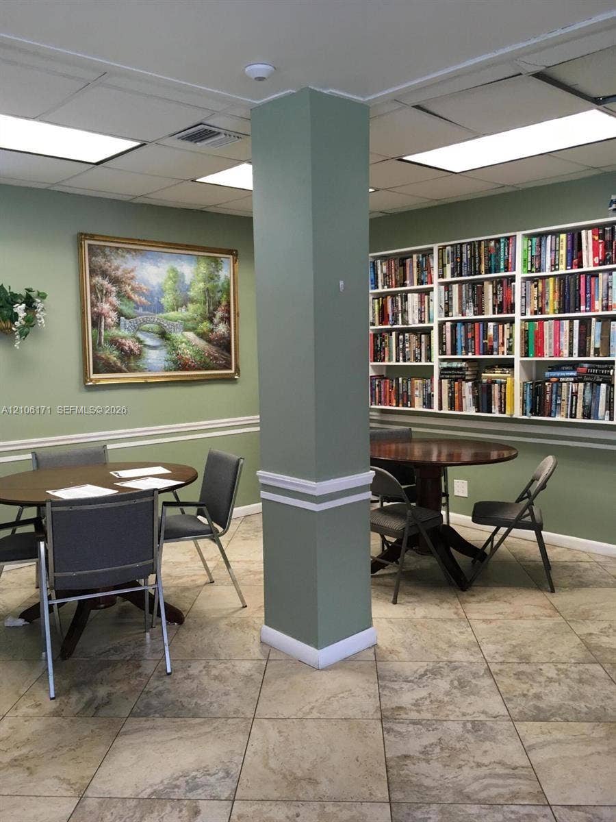 Built-in floor-to-ceiling white shelving, neutral stone-finish tile flooring, recessed ceiling lighting, and chair rail molding