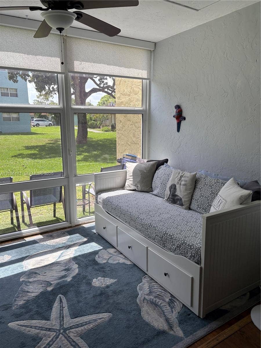 Enclosed porch featuring floor-to-ceiling windows, retractable solar shades, and a ceiling fan