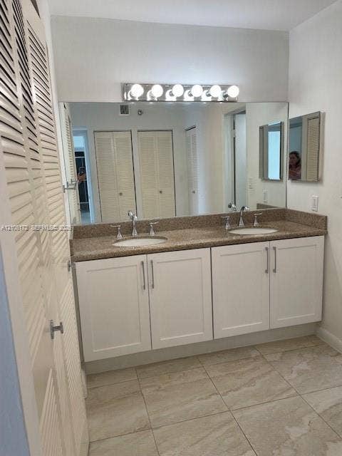20515 E Country Club Drive, #246, Aventura, Aventura, FL 33180 Double vanity featuring white cabinetry, stone-finish countertops, dual drop-in sinks, polished metal hardware, and a full-width wall mirror