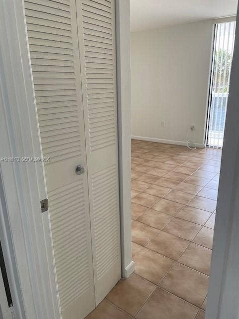 20515 E Country Club Drive, #246, Aventura, Aventura, FL 33180 Bi-fold louvered closet doors, neutral ceramic tile flooring, and vertical blinds covering a floor-to-ceiling glass door