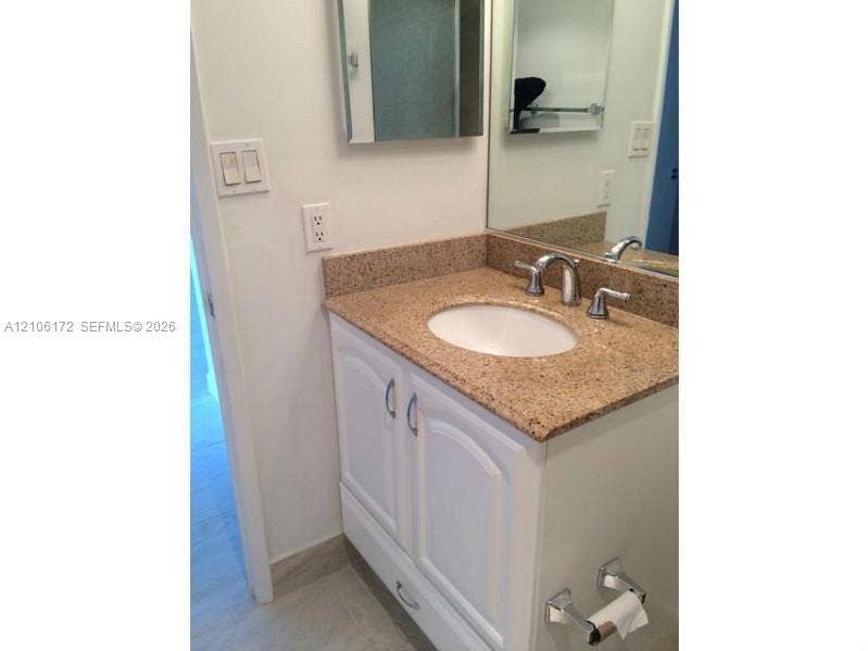 20515 E Country Club Drive, #246, Aventura, Aventura, FL 33180 Vanity featuring a stone-composite countertop, white shaker-style cabinetry, an integrated oval basin, and a dual-handle chrome faucet