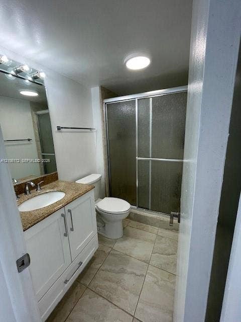 20515 E Country Club Drive, #246, Aventura, Aventura, FL 33180 Bathroom featuring white cabinetry, stone-surface vanity top with an integrated sink, tiled flooring, and a walk-in shower with a sliding glass enclosure