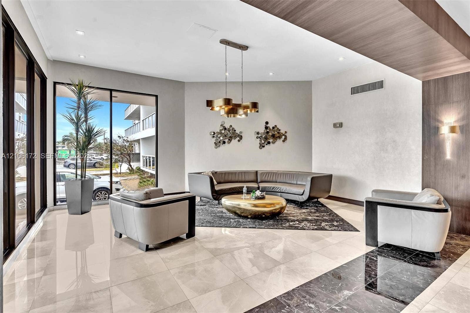 20515 E Country Club Drive, #246, Aventura, Aventura, FL 33180 Spacious lobby area featuring large-format polished tile flooring, wood-finish ceiling detailing, metallic multi-pendant lighting, and floor-to-ceiling glass panels