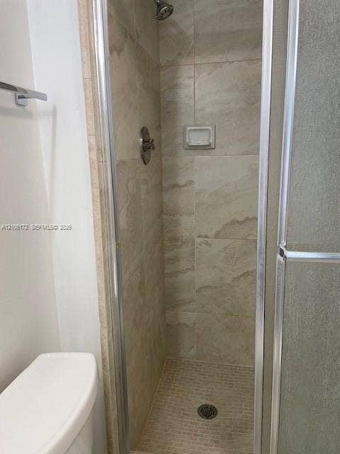 20515 E Country Club Drive, #246, Aventura, Aventura, FL 33180 Walk-in shower featuring floor-to-ceiling stone-finish wall tile, mosaic tile shower floor, integrated recessed soap dish, metal-frame glass door, and adjustable shower head