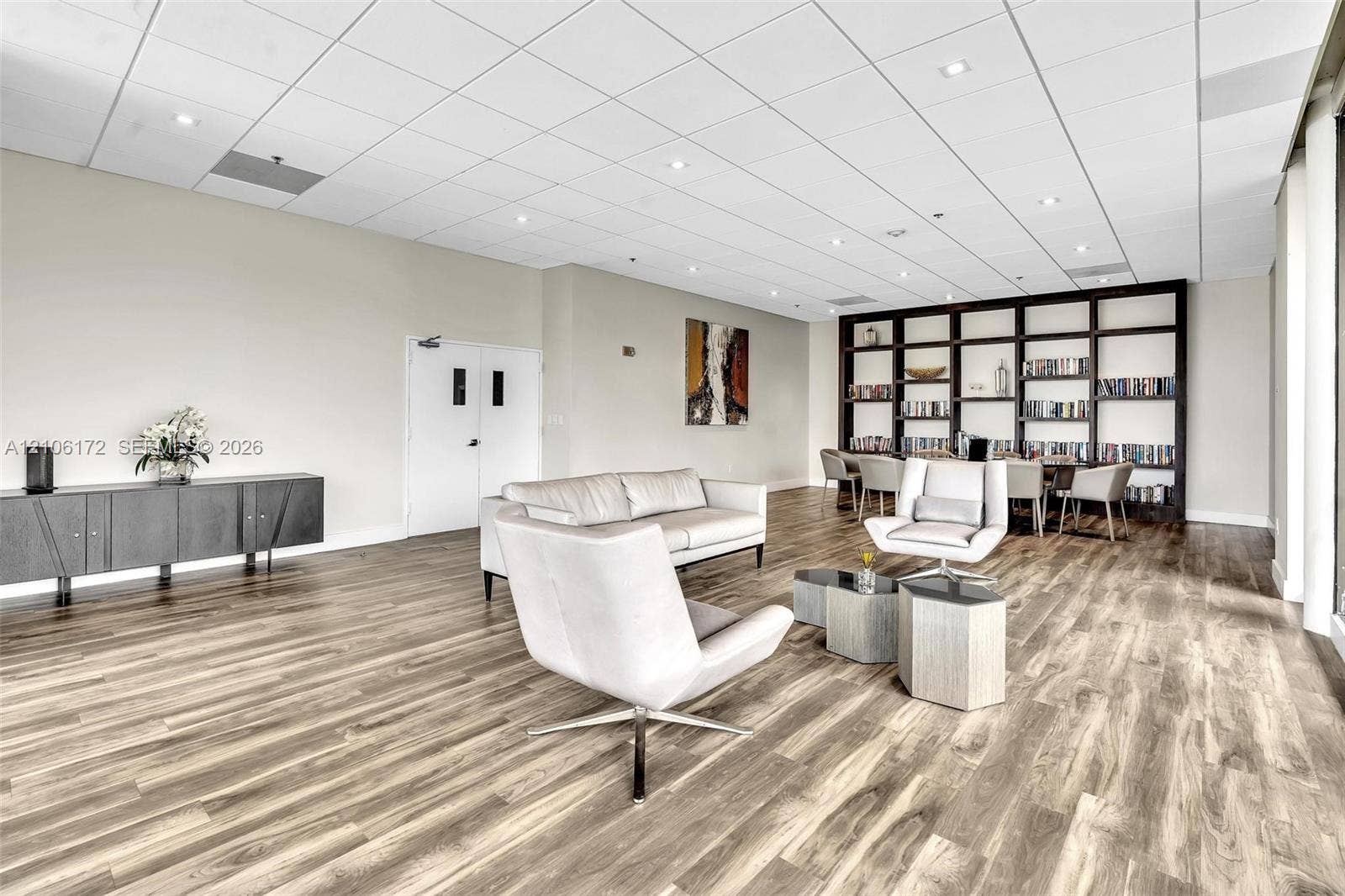 20515 E Country Club Drive, #246, Aventura, Aventura, FL 33180 Expansive interior featuring wood-finish flooring, a full-height built-in dark wood shelving unit, recessed lighting, and a drop-tile ceiling