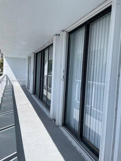20515 E Country Club Drive, #246, Aventura, Aventura, FL 33180 Covered balcony featuring concrete flooring, white metal railing, and multiple floor-to-ceiling sliding glass doors with dark frames