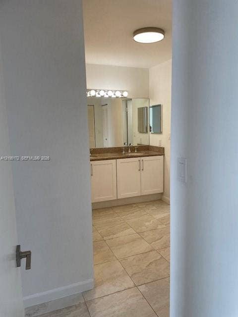 20515 E Country Club Drive, #246, Aventura, Aventura, FL 33180 Bathroom featuring white shaker-style cabinetry, solid-surface countertop with dual integrated sinks, large vanity mirror, multi-bulb overhead lighting, and neutral floor tiling