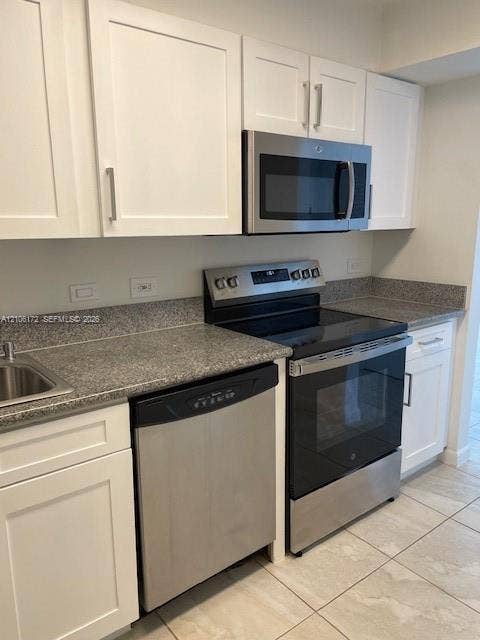 20515 E Country Club Drive, #246, Aventura, Aventura, FL 33180 White shaker-style cabinetry, stone-finish countertops, stainless steel appliances, and tiled flooring