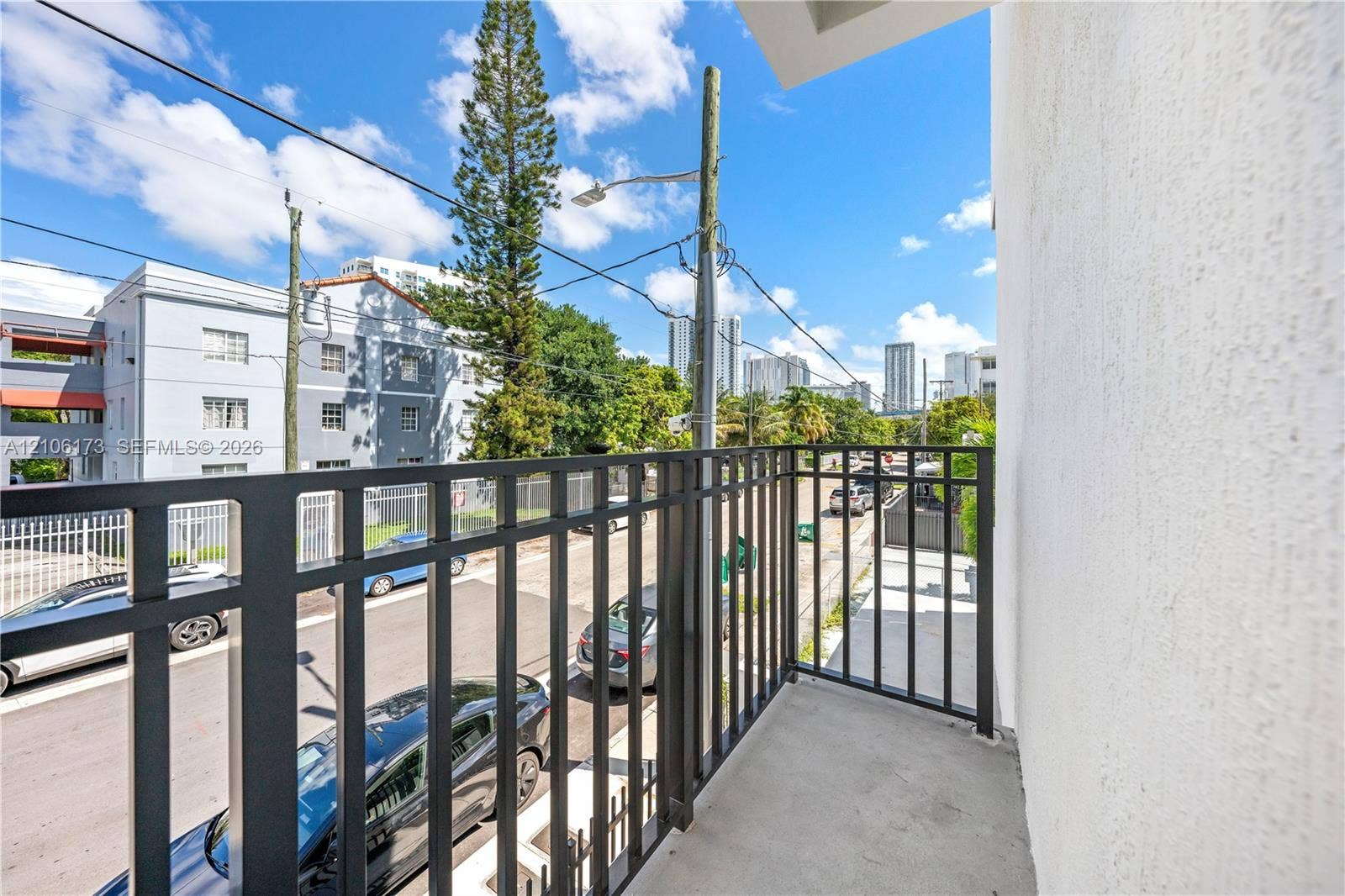 Covered exterior balcony featuring a concrete floor and a matte black metal railing