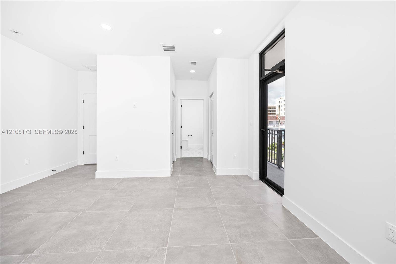 Interior featuring large-format ceramic tile flooring, recessed lighting, and a full-height glass door with a black frame