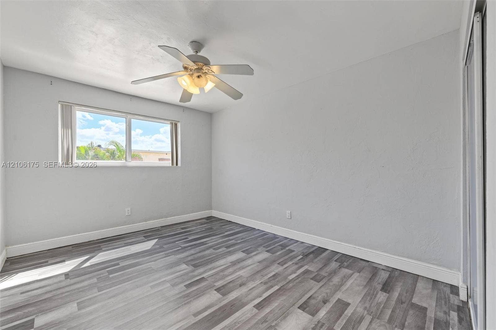 6905 W 2nd Way, #1, Hialeah, Hialeah, FL 33014 Room featuring wood-finish flooring, a multi-blade ceiling fan with integrated lighting, and a sliding door closet