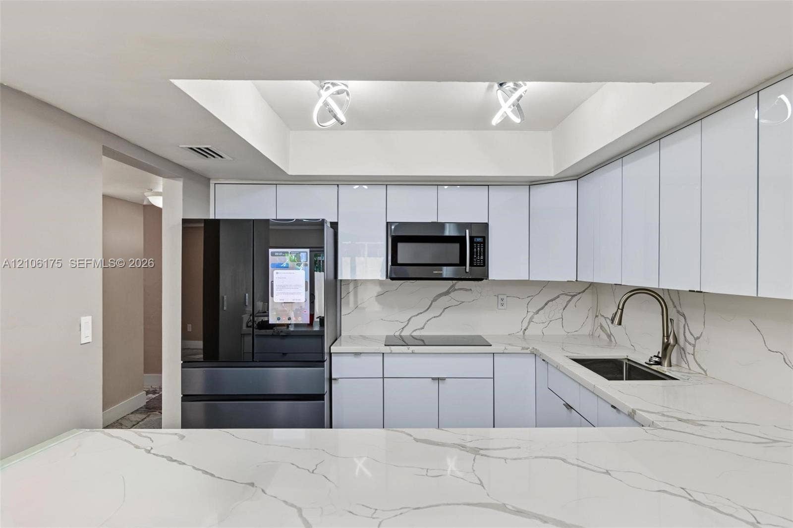 6905 W 2nd Way, #1, Hialeah, Hialeah, FL 33014 Kitchen featuring high-gloss white cabinetry, stone-patterned countertops, a matching full-height backsplash, a stainless steel undermount sink with a gooseneck faucet, and recessed tray ceiling lighting