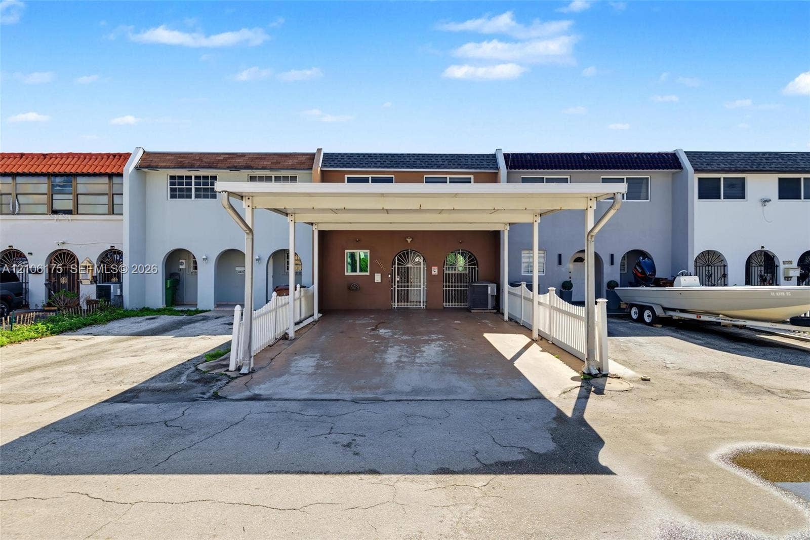 6905 W 2nd Way, #1, Hialeah, Hialeah, FL 33014 Covered carport featuring a metal structural frame, white vinyl perimeter fencing, and dual metal security entry doors