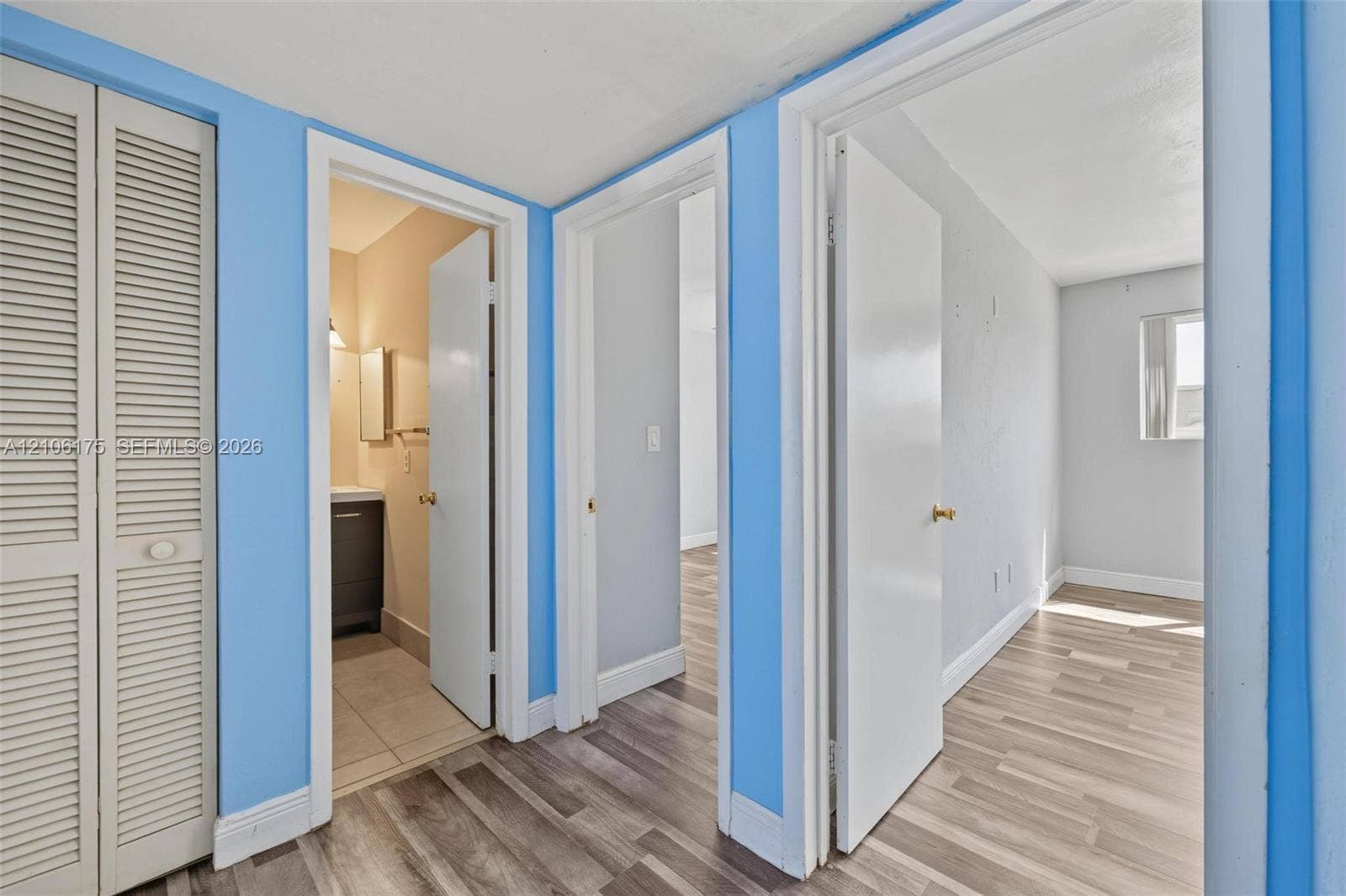 6905 W 2nd Way, #1, Hialeah, Hialeah, FL 33014 Interior hall featuring louvered bi-fold closet doors, wood-finish flooring, and multiple doorways leading to interior rooms