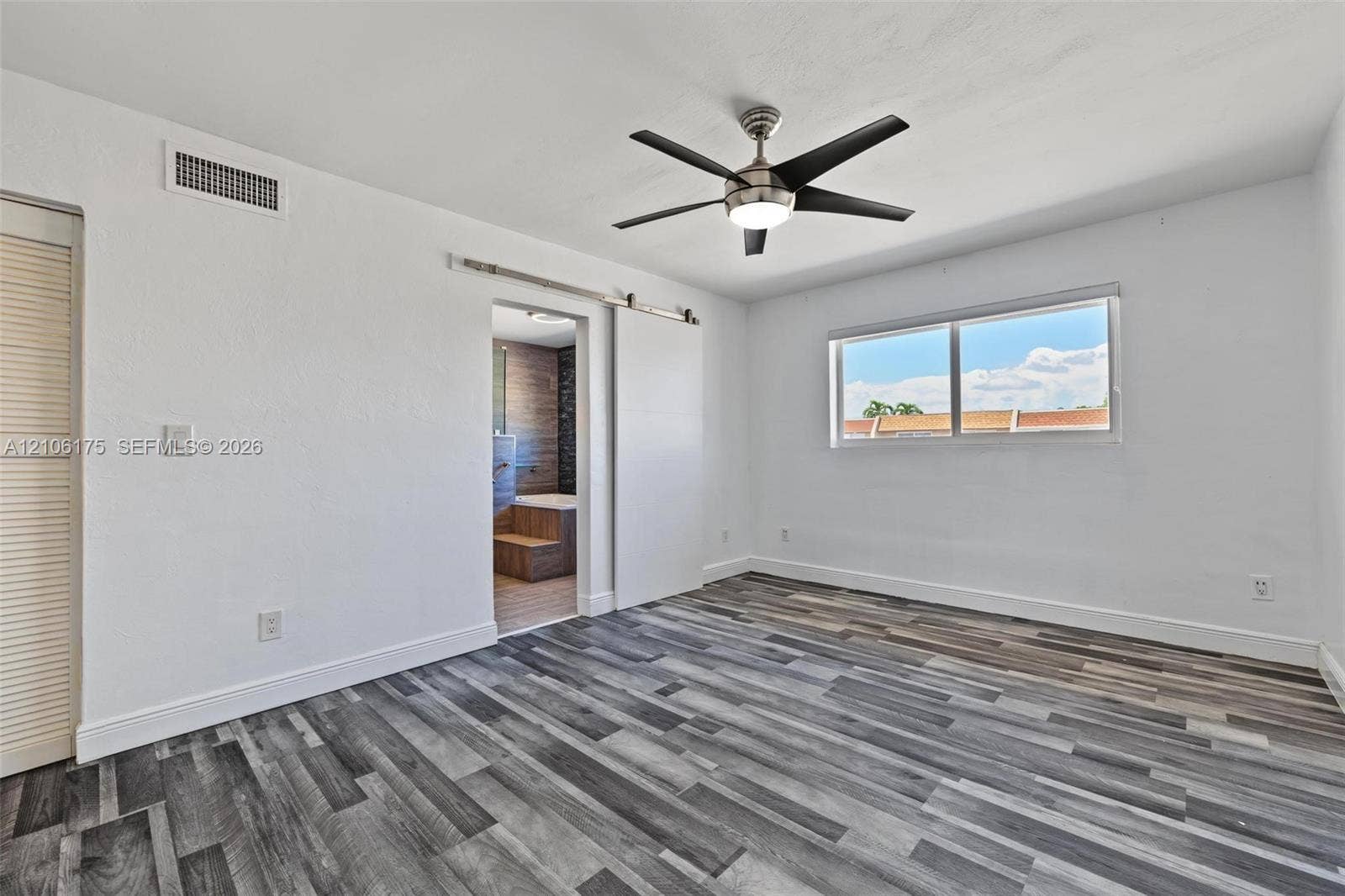 6905 W 2nd Way, #1, Hialeah, Hialeah, FL 33014 Room featuring wood-finish flooring, a sliding barn-style door, and a ceiling fan with integrated lighting