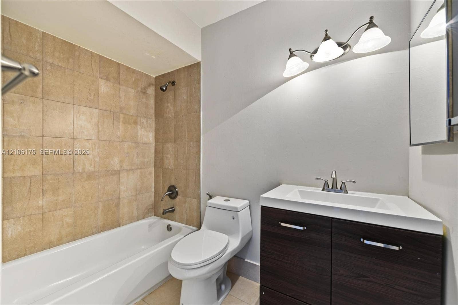6905 W 2nd Way, #1, Hialeah, Hialeah, FL 33014 Bathroom featuring a dark wood-finish vanity, white rectangular sink, three-light fixture, and a tub enclosure with neutral square tile surround