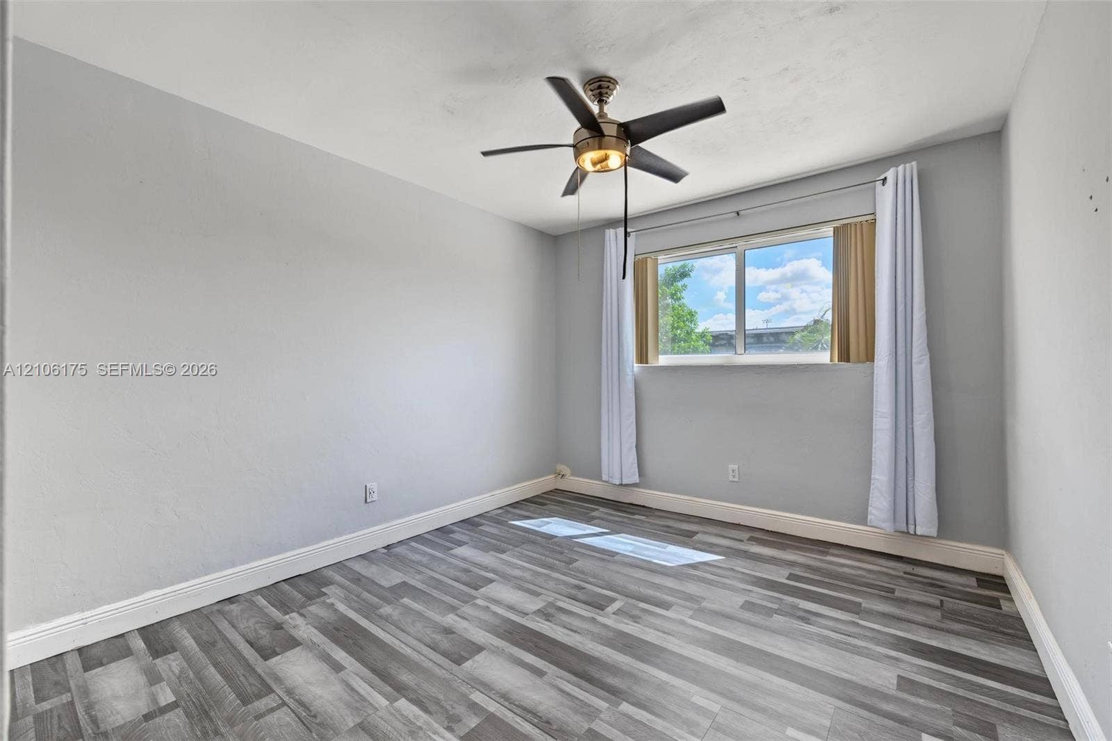 6905 W 2nd Way, #1, Hialeah, Hialeah, FL 33014 Neutral-toned interior featuring wood-finish flooring, a multi-blade ceiling fan with integrated lighting, and a single-pane window