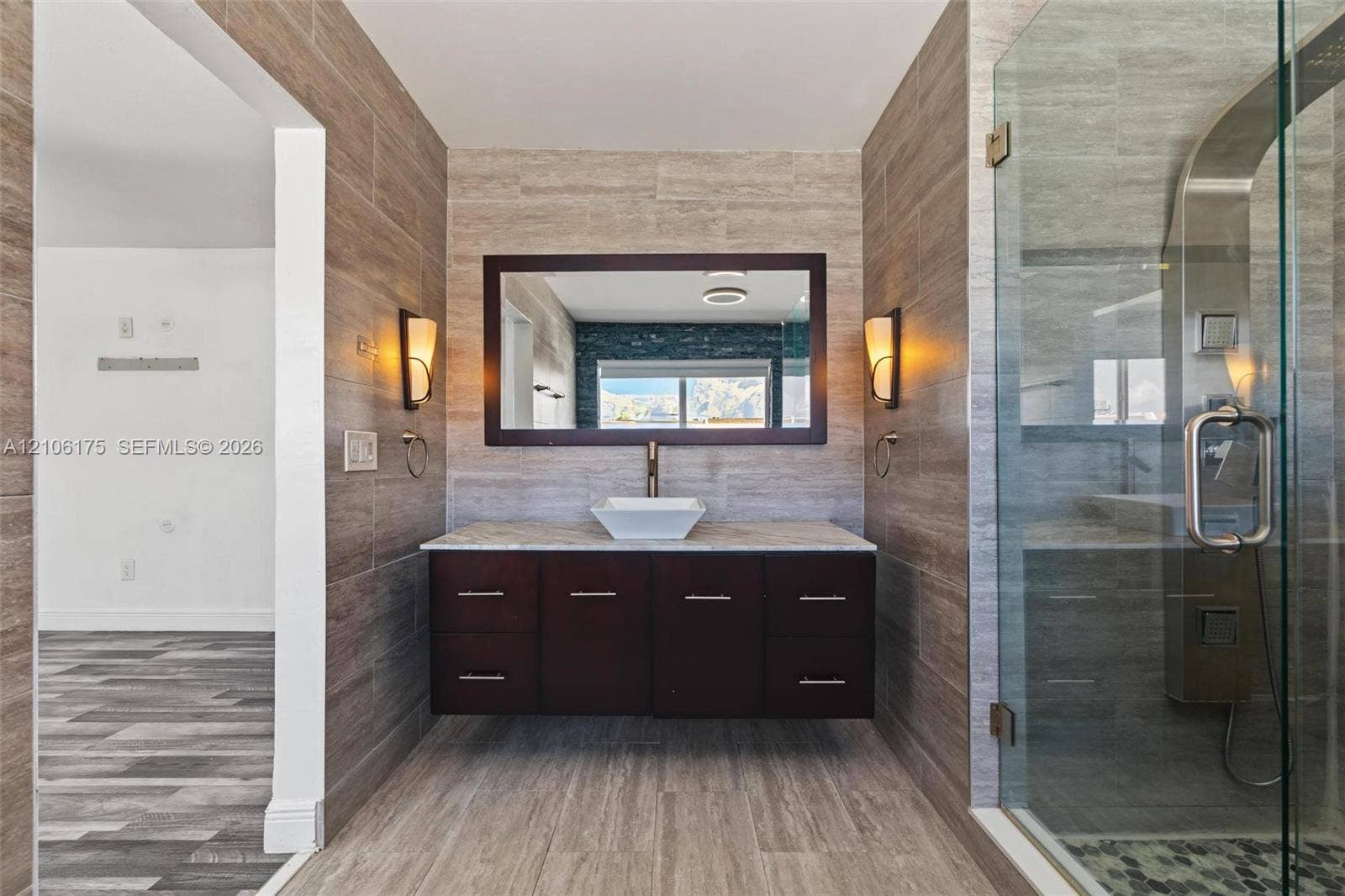 6905 W 2nd Way, #1, Hialeah, Hialeah, FL 33014 Floating dark wood vanity with a stone countertop, rectangular vessel sink, full-height wall tiling, glass-enclosed shower, and wall-mounted sconces